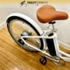A partial view of a 2023 white electric bike with a brown saddle, showcasing the rear wheel, 350W black battery, and pedal mechanism. The Serfas eDART 2023 350W bike is positioned on a wooden floor with a plain white wall in the background. The logo "Crazy Lennyโs Electric Bikes" is visible at the top. A partial view of a 2023 white electric bike with a brown saddle, showcasing the rear wheel, 350W black battery, and pedal mechanism. The Serfas eDART 2023 350W bike is positioned on a wooden floor with a plain white wall in the background. The logo "Crazy Lennyโs Electric Bikes" is visible at the top.