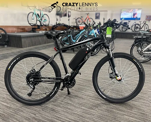 An EG Kyoto (Demo) electric bike is displayed in a showroom with several other bikes in the background. The bike is black with thick tires, a central battery, and appears to be a hybrid mountain style. Serving as a demo model, the showroom showcases Crazy Lenny's Electric Bikes logo at the top.