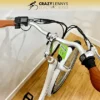 A white Serfas eDART 2023 350W with brown handle grips is displayed indoors on a wooden floor. A digital display is mounted on the left handlebar and a green price tag is attached to the frame, indicating its 350W motor. The logo "Crazy Lenny's Electric Bikes" is visible at the top of the image. A white Serfas eDART 2023 350W with brown handle grips is displayed indoors on a wooden floor. A digital display is mounted on the left handlebar and a green price tag is attached to the frame, indicating its 350W motor. The logo "Crazy Lenny's Electric Bikes" is visible at the top of the image.