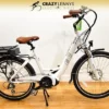 An electric bicycle on display with a white frame, brown seat, and black handlebars. It features a rear rack with a battery pack, front and rear fenders, and a kickstand. The EG Athens 350MD Mid Drive model also boasts a powerful mid-drive motor. The background includes the logo of "Crazy Lenny's Electric Bikes. An electric bicycle on display with a white frame, brown seat, and black handlebars. It features a rear rack with a battery pack, front and rear fenders, and a kickstand. The EG Athens 350MD Mid Drive model also boasts a powerful mid-drive motor. The background includes the logo of "Crazy Lenny's Electric Bikes.