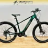 A green Reid E-Trail 2.0 MY23 electric mountain bike is displayed indoors against a white wall and wooden floor. The bike features a sturdy frame, front suspension, and large tires suitable for off-road riding. The text "Crazy Lenny's Electric Bikes" is visible at the top. A green Reid E-Trail 2.0 MY23 electric mountain bike is displayed indoors against a white wall and wooden floor. The bike features a sturdy frame, front suspension, and large tires suitable for off-road riding. The text "Crazy Lenny's Electric Bikes" is visible at the top.