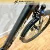 A close-up of a black Reid Quest 1.0 MY23 electric bike, focusing on the front tire, fork, and part of the frame. The bike is on a wooden floor with a white wall in the background. The logo "CRAZY LENNY'S ELECTRIC BIKES" is visible at the top of the image. A close-up of a black Reid Quest 1.0 MY23 electric bike, focusing on the front tire, fork, and part of the frame. The bike is on a wooden floor with a white wall in the background. The logo "CRAZY LENNY'S ELECTRIC BIKES" is visible at the top of the image.