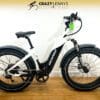 A white Denago Fat Tire Step-Thru with black detailing is displayed against a white wall. The Step-Thru bike features thick fat tires, front suspension, and a black seat. "Crazy Lenny's Electric Bikes" is displayed at the top against a yellow gradient background. A white Denago Fat Tire Step-Thru with black detailing is displayed against a white wall. The Step-Thru bike features thick fat tires, front suspension, and a black seat. "Crazy Lenny's Electric Bikes" is displayed at the top against a yellow gradient background.