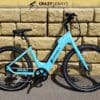 A bright blue Serfas eDASH electric bike with the brand name "Dash" is parked against a wall made of large, tan bricks. The bike boasts a sporty design with black Serfas handlebars, a black seat, and black tires. Above the bike, there's a "Crazy Lenny's Electric Bikes" logo. A bright blue Serfas eDASH electric bike with the brand name "Dash" is parked against a wall made of large, tan bricks. The bike boasts a sporty design with black Serfas handlebars, a black seat, and black tires. Above the bike, there's a "Crazy Lenny's Electric Bikes" logo.