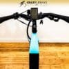 Close-up of Serfas eDASH handlebars with a built-in screen, brake levers, and Serfas grips. The background features a wooden floor and a white wall adorned with the "Crazy Lenny's Electric Bikes" logo. Keys dangle from the bike's handlebars. Close-up of Serfas eDASH handlebars with a built-in screen, brake levers, and Serfas grips. The background features a wooden floor and a white wall adorned with the "Crazy Lenny's Electric Bikes" logo. Keys dangle from the bike's handlebars.