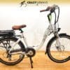 A white electric bike with "EG Athens 350DX Hub Drive" branding on the frame, brown saddle and handlebar grips, and a rear-mounted battery pack is displayed on a wooden floor. The image background features a gradient with "Crazy Lenny's Electric Bikes" text and logo at the top.