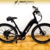 A black electric bike by Crazy Lenny's Electric Bikes is displayed against a white wall with a wooden floor. The Serfas eDASH bike has a sleek frame, large tires, and a comfortable saddle. The branding "DASH" is visible on the frame.