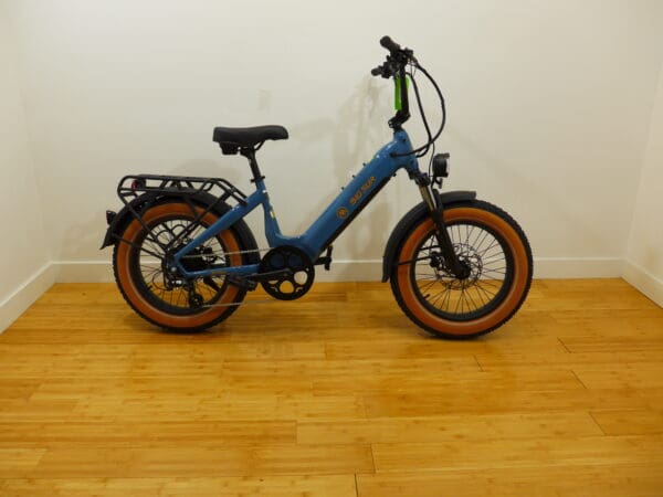 Blue electric bicycle with brown tires indoors.