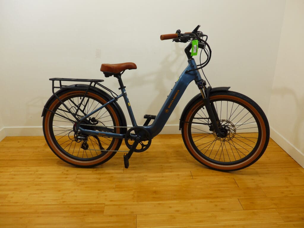 Blue electric bicycle with wooden floor background.