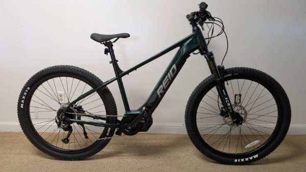 Green Reid mountain bike on carpeted floor.