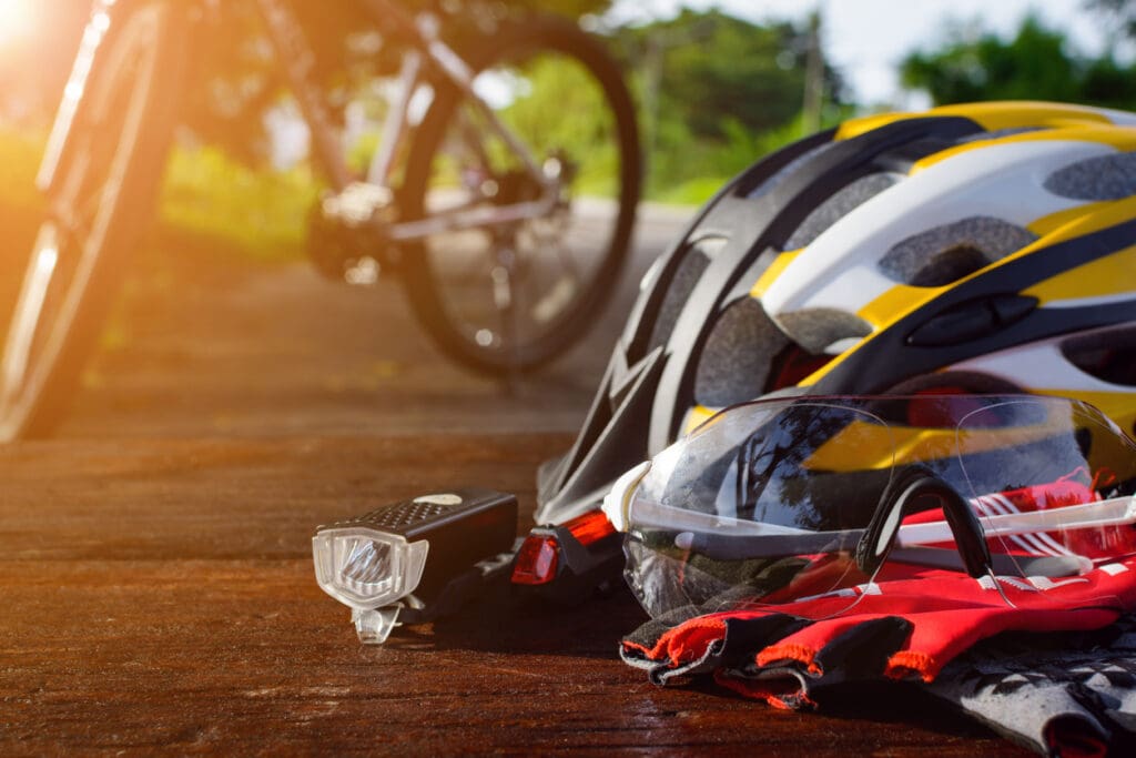Cycling gear with helmet and gloves on wooden surface.