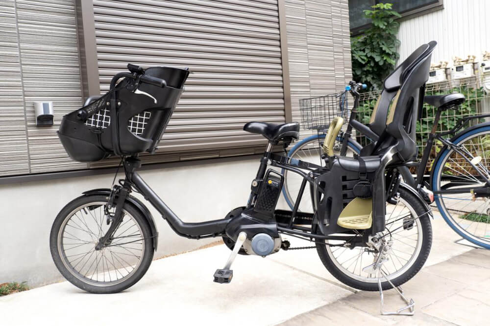 Electric bike with child seats parked outside.