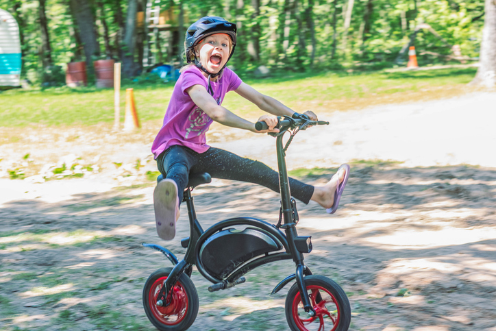 Excited child riding bike with one foot up.