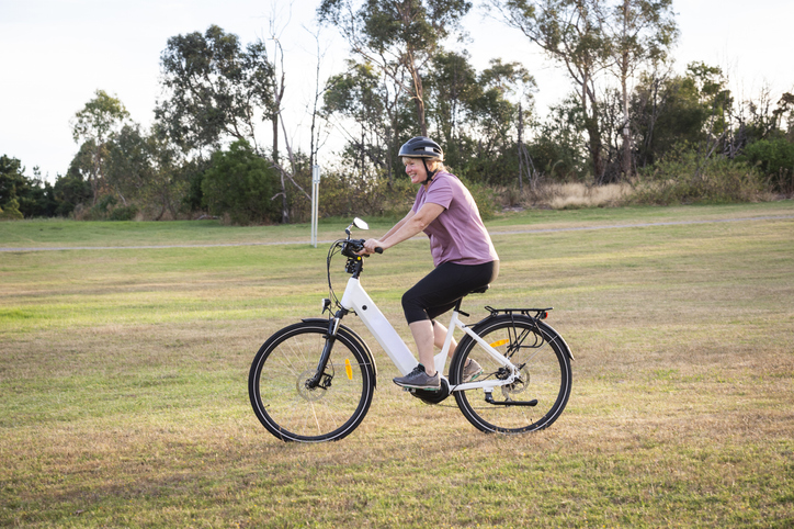 Person riding an electric bike in a grassy field.