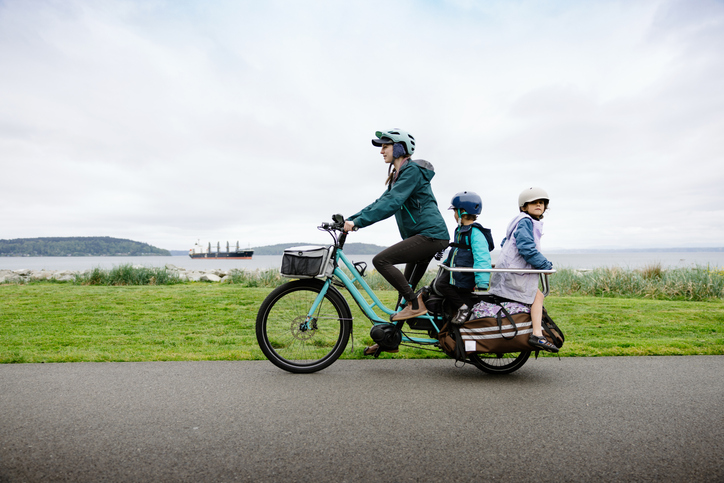 Family cycling by the seaside on a cargo bike.