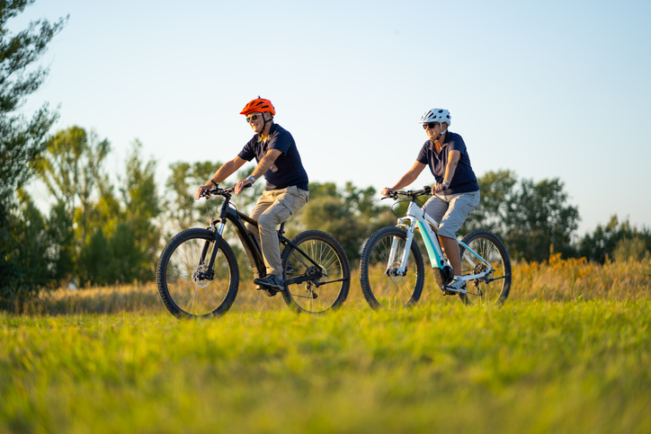 Two people cycling in a sunny field.