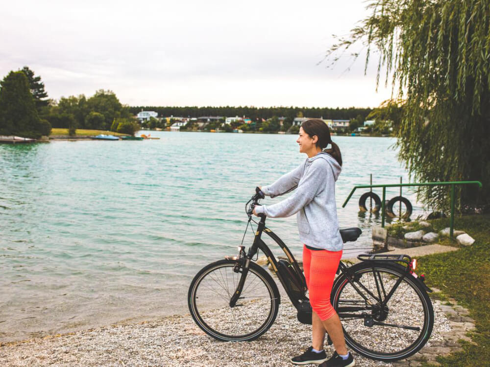 Woman with bike by scenic lake view