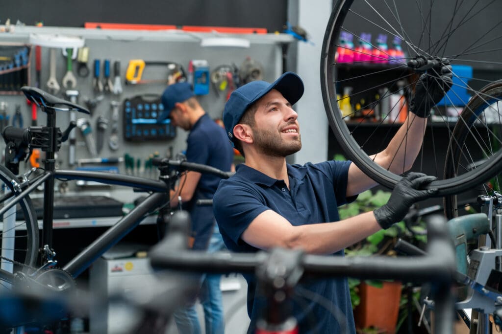 Mechanic fixing bicycle wheel in workshop.