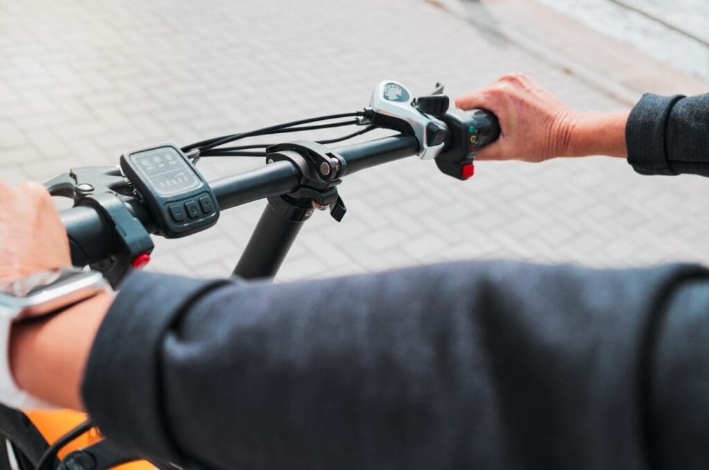 Person riding electric bike, focus on handlebars display