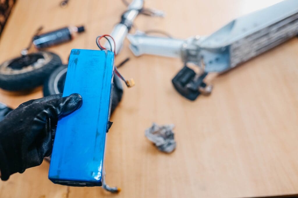 Person holding electric scooter battery on table.