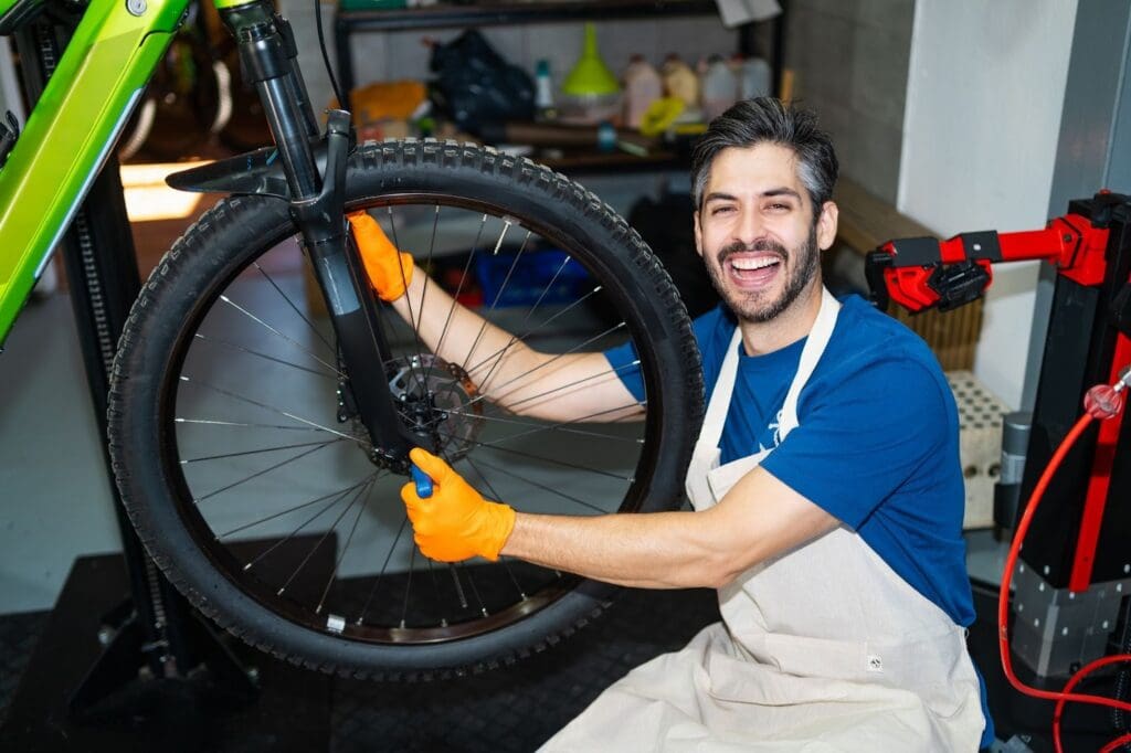 Smiling mechanic fixing bike in workshop