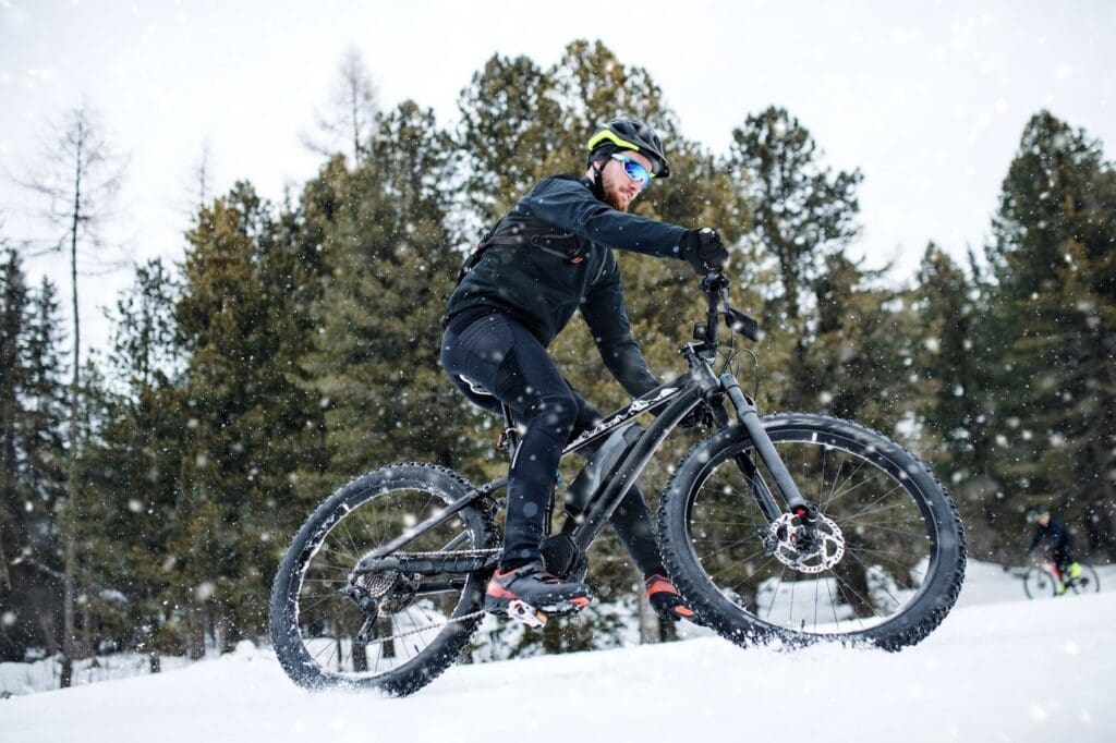 Cyclist riding mountain bike in snowy forest