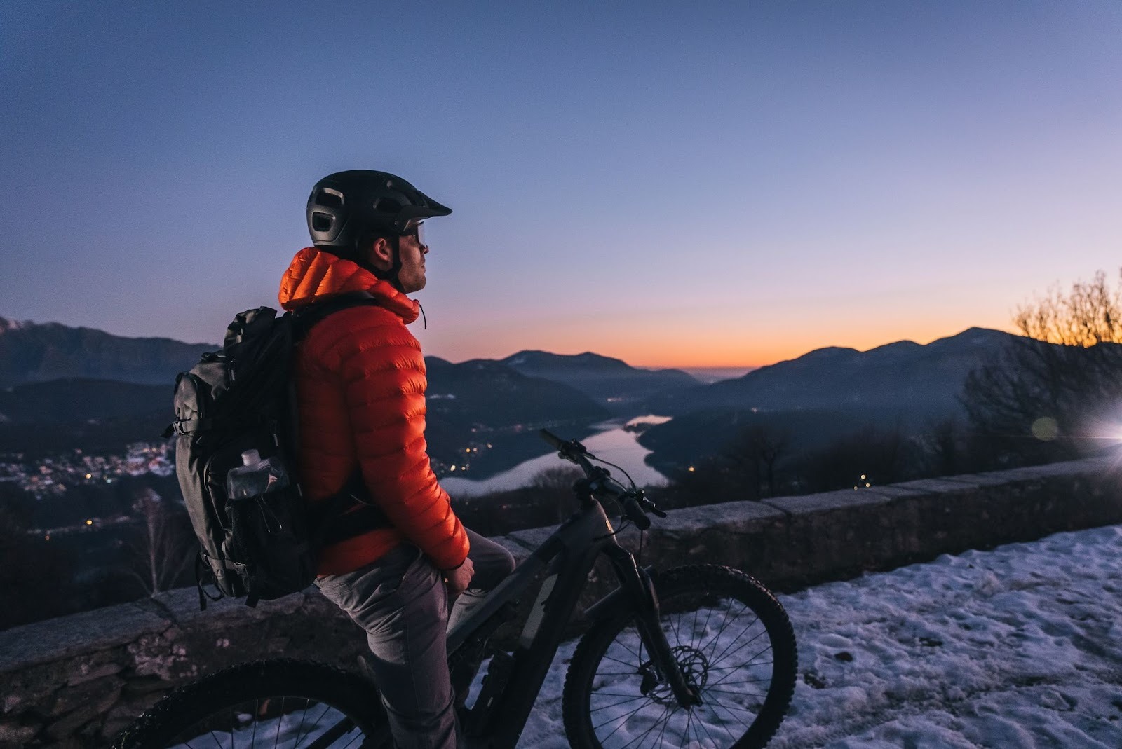 Cyclist overlooking snowy mountain sunset view.