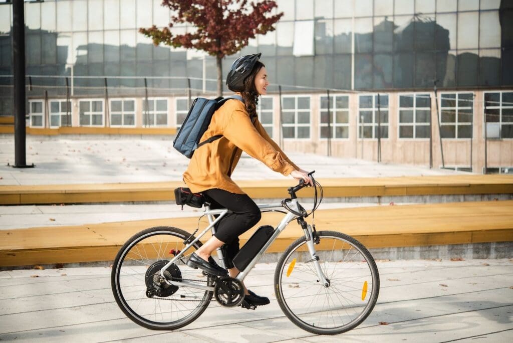 Person cycling with a backpack in urban area.