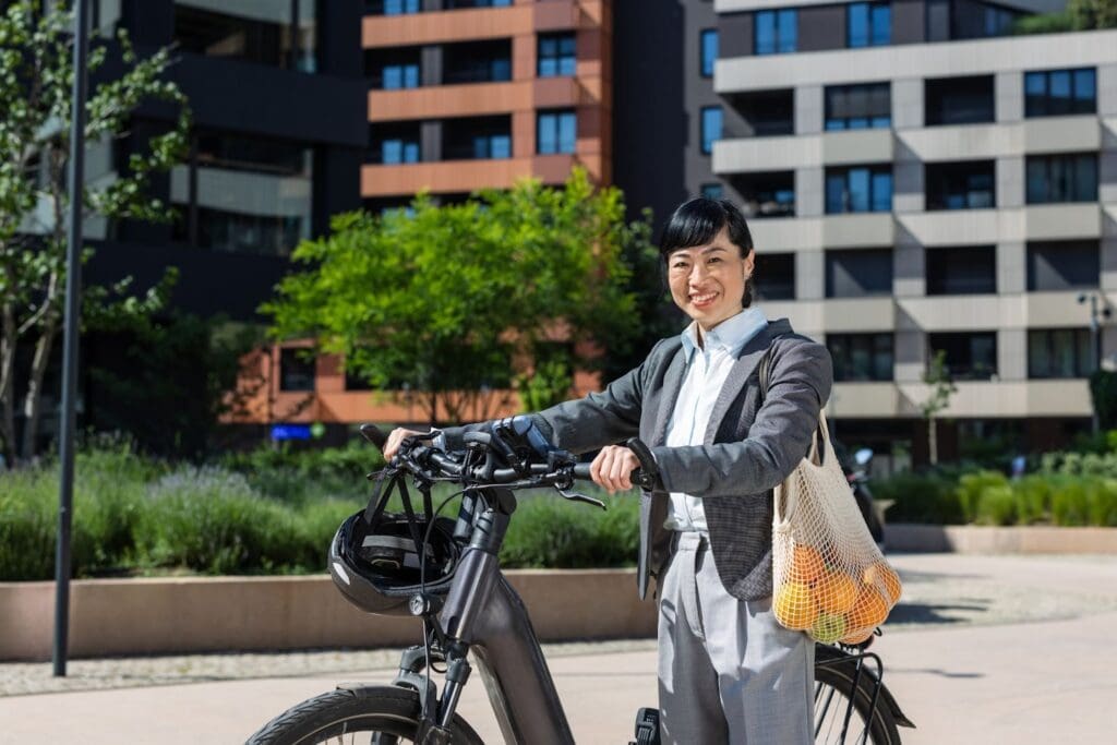 Smiling person with e-bike and groceries outdoors.