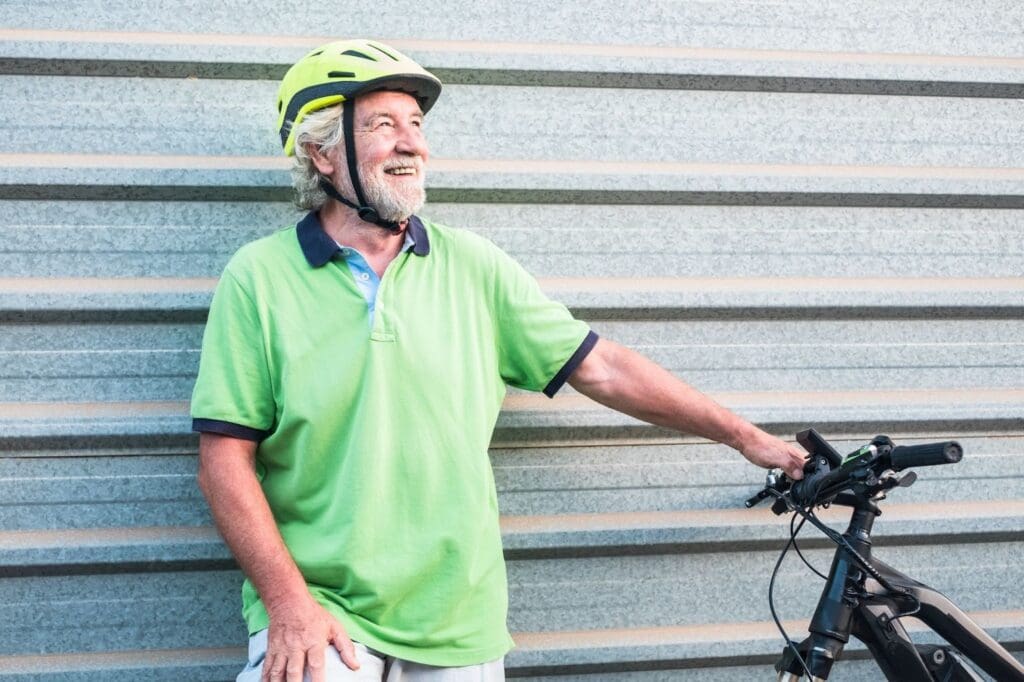 Smiling man with bike and helmet outdoors.