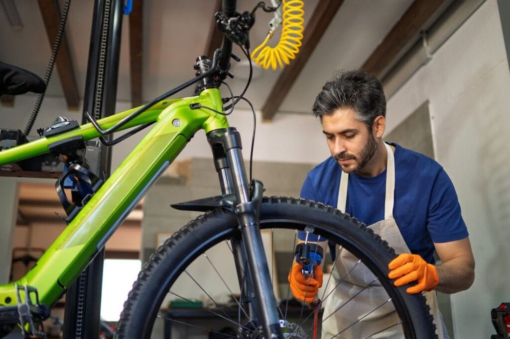 Mechanic repairing a green bicycle in workshop.