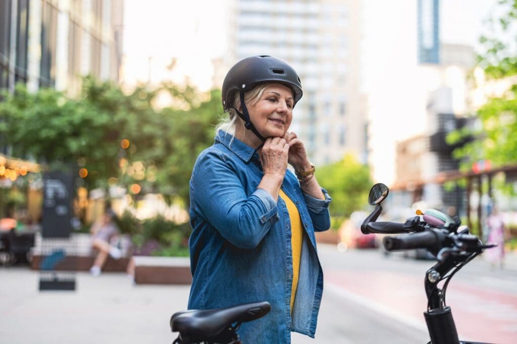 Woman fastening helmet beside electric scooter.
