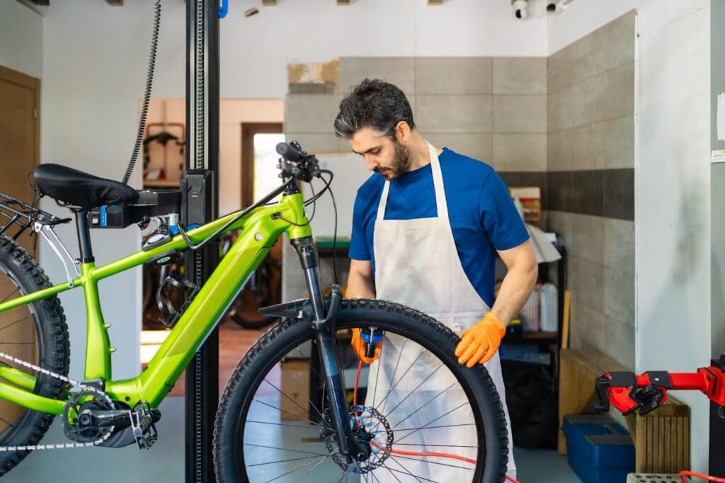 Mechanic repairing green bicycle in workshop.