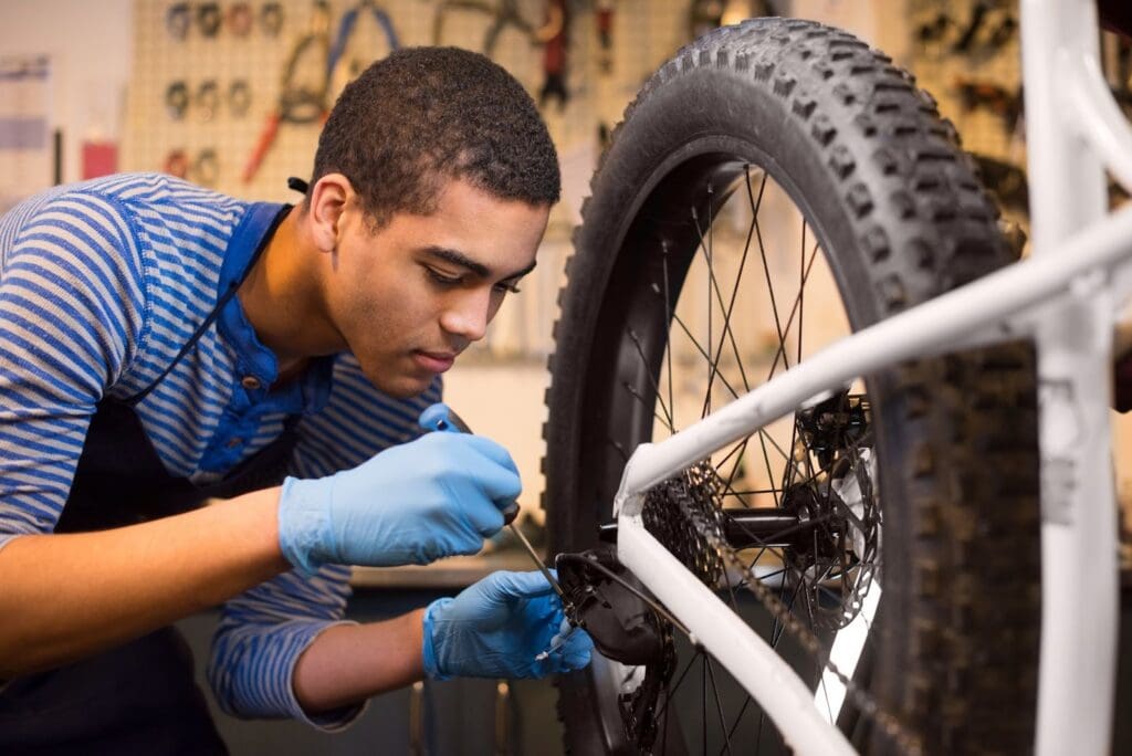 Man repairing bicycle wheel in workshop.