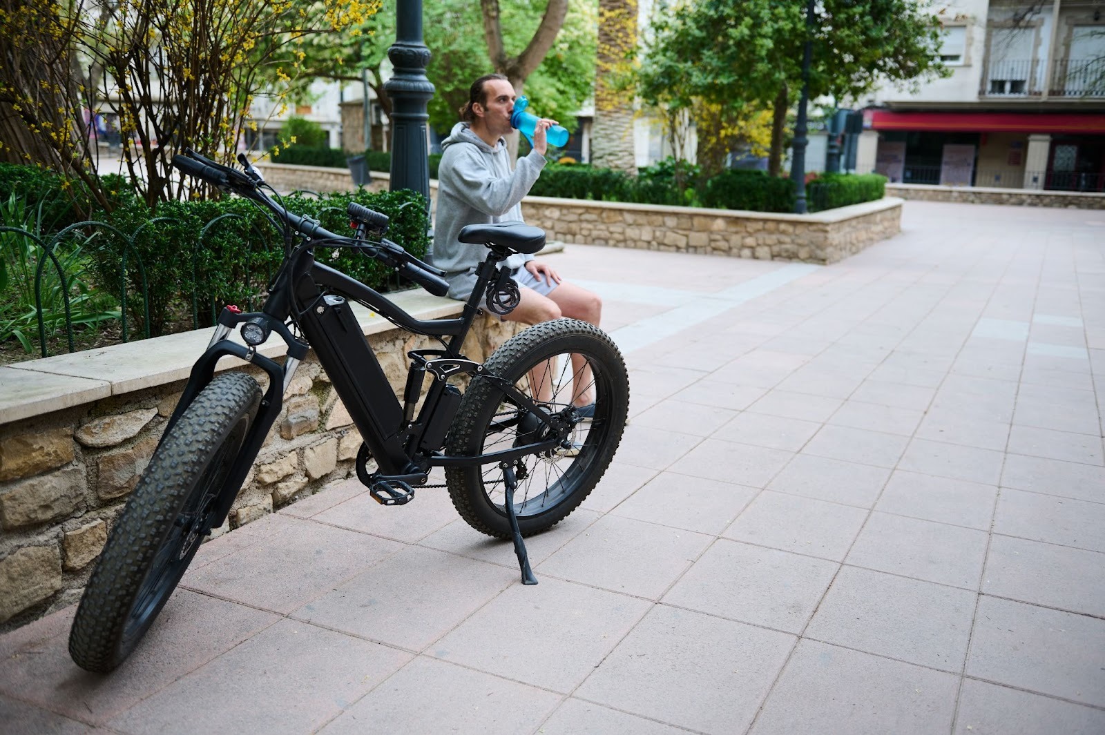 Person on bench drinking water near electric bike.