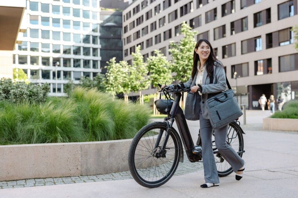 Person walking bicycle in urban park setting.