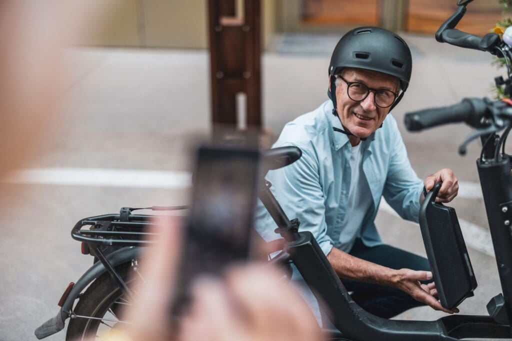 Man holding electric bike battery outdoors.