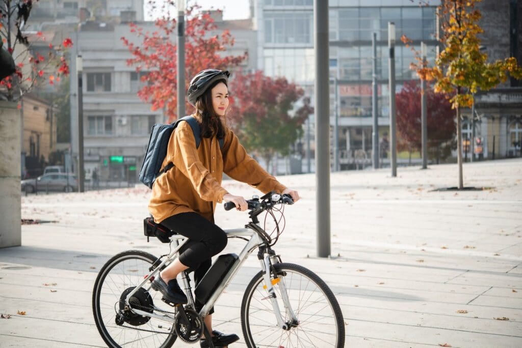 Person biking in urban setting with autumn trees