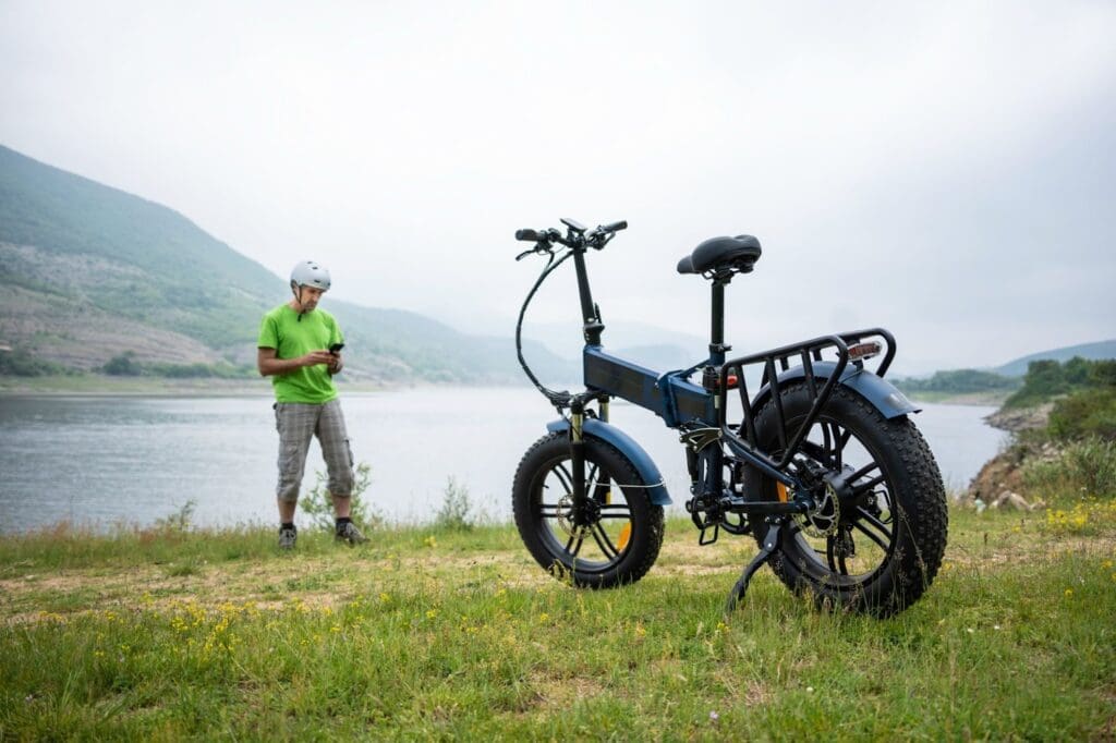 Man with helmet near electric bike by lake