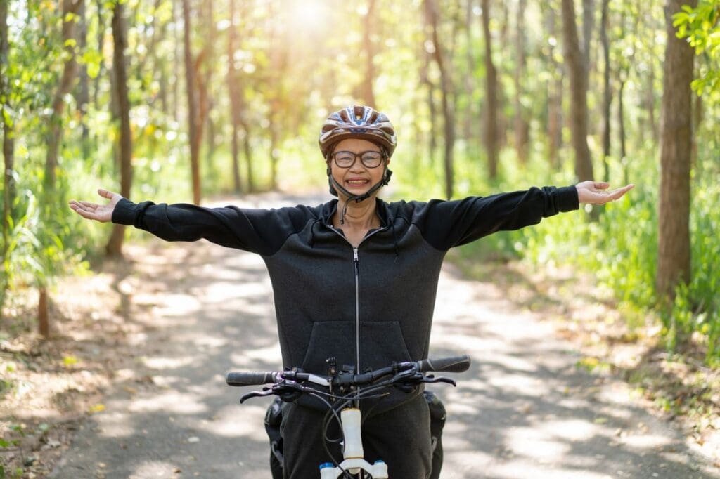 Joyful cyclist with arms outstretched in forest.