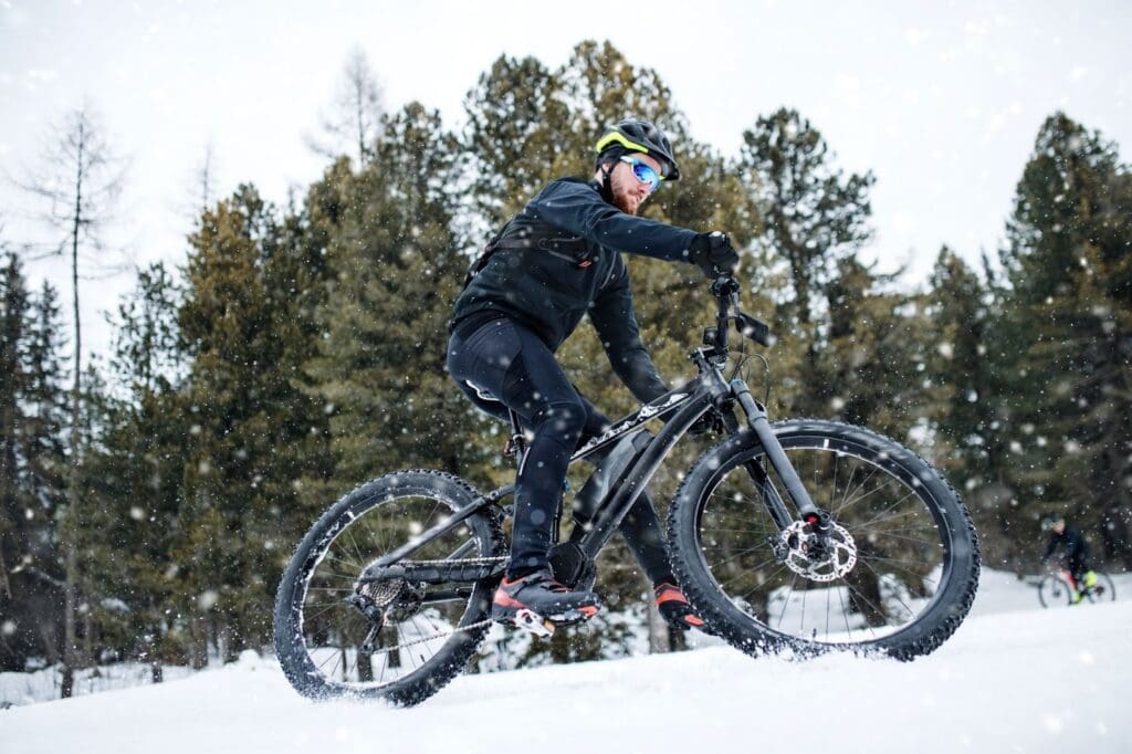 Cyclist riding mountain bike in snowy forest.
