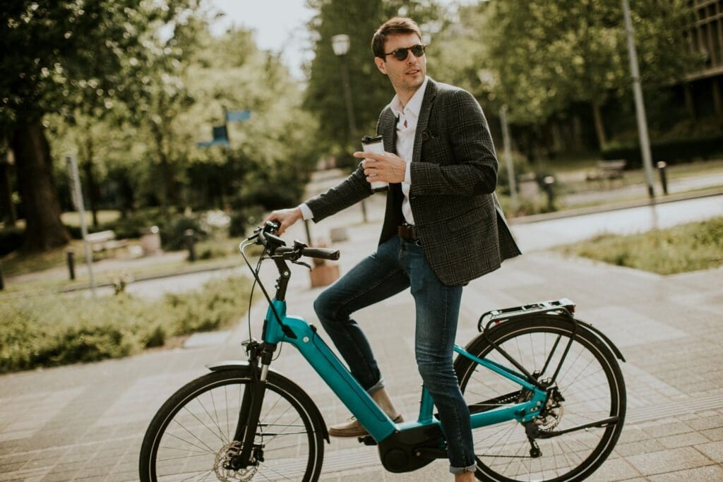Man riding electric bike holding coffee cup