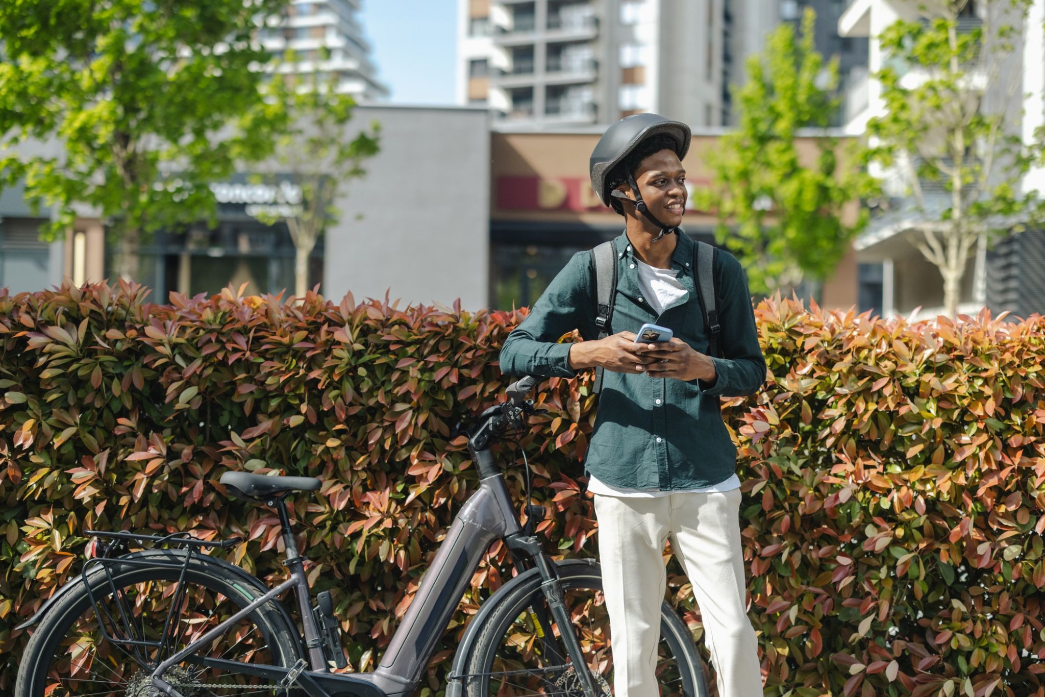 Man with helmet using phone beside e-bike