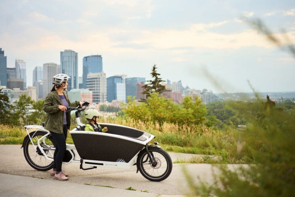 Woman with child on cargo bike overlooking city skyline