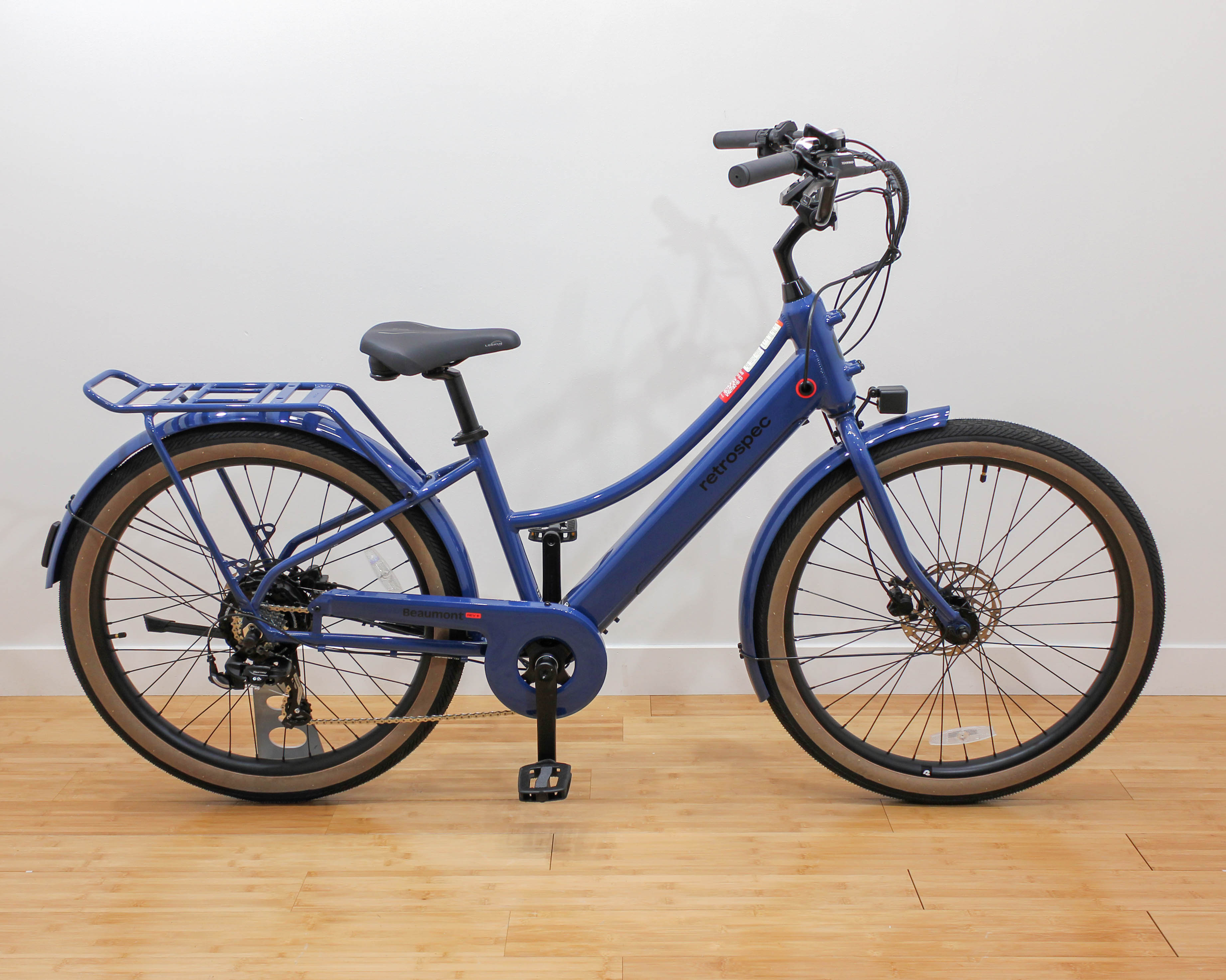 Blue step-through electric bicycle with rear rack indoors