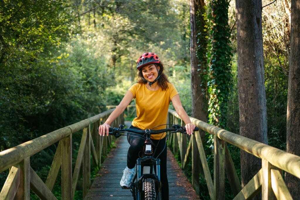 Woman cycling on wooden bridge in forest