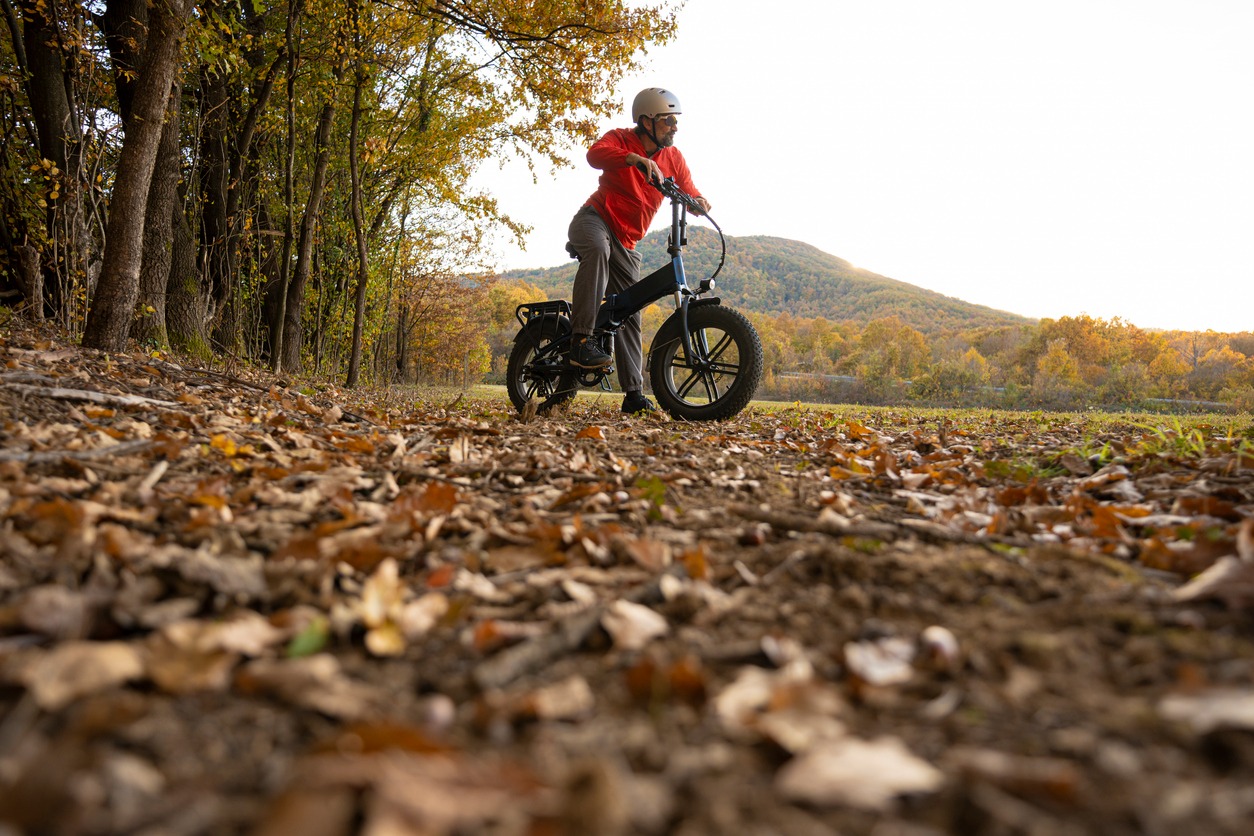 Man riding electric bike through autumn forest