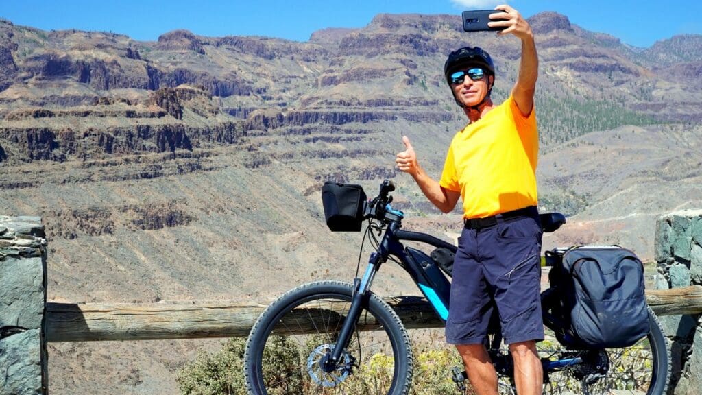 Cyclist taking selfie with mountain canyon backdrop