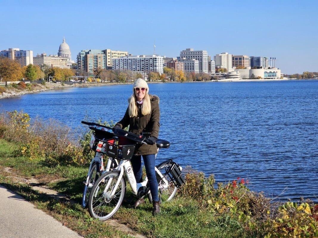 Woman with electric bike by lakeside city skyline